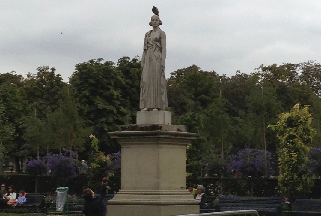 Young boy offering his ball to bare-brested woman with pidgeon on her head